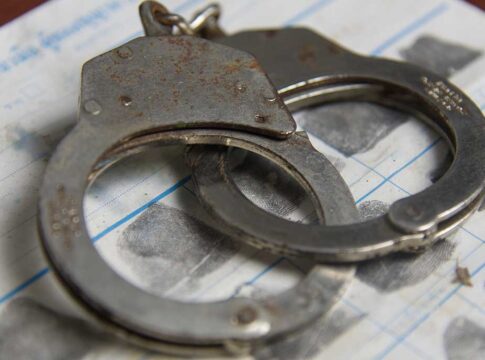 Rusty handcuffs on fingerprint document.