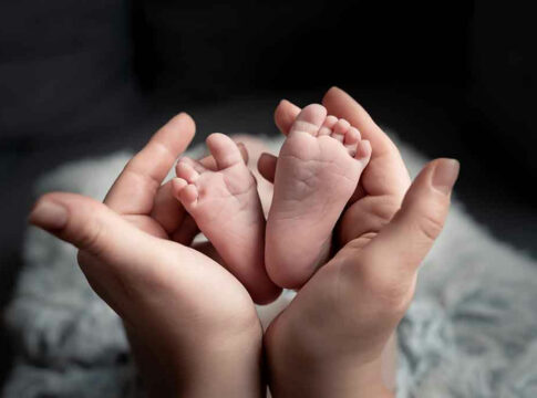 Hands holding newborn babys feet.