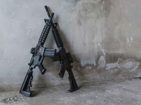 Two rifles leaning against a concrete wall.