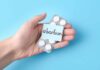 Hand holding pills labeled "abortion" on blue background.