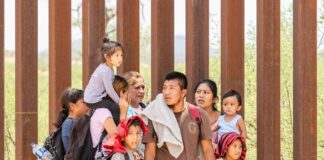 Group of people standing by a metal fence.