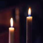Two lit candles in the dark background.