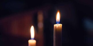 Two lit candles in the dark background.