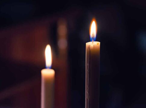 Two lit candles in the dark background.