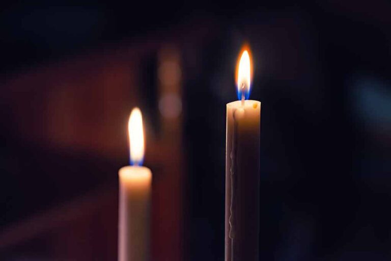 Two lit candles in the dark background.