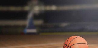 Basketball on an indoor court, hoop in background.