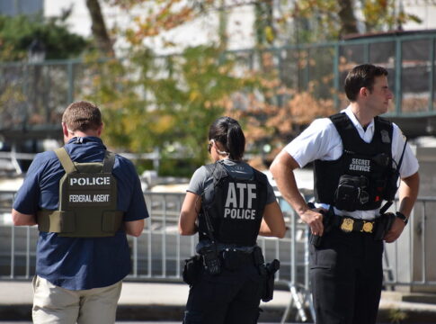 Authorities standing together outdoors wearing law enforcement gear