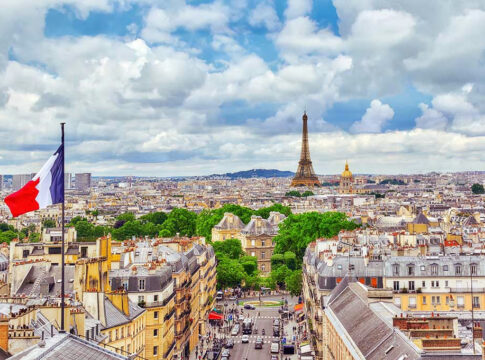 Eiffel Tower view with French flag and cityscape.