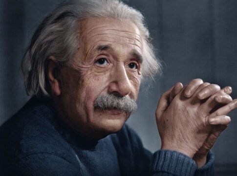 Close-up portrait of an elderly man with gray hair and a thoughtful expression, hands clasped together