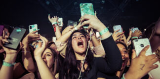 Concert crowd cheering and taking photos with phones.