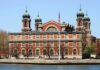 Historic Ellis Island building with green domes and American flag in front