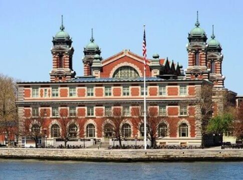 Historic Ellis Island building with green domes and American flag in front