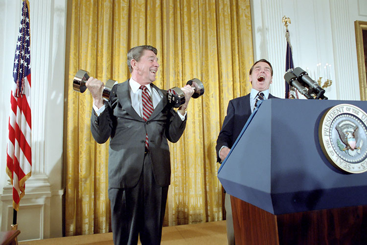U.S. President Ronald Reagan lifting dumbbells during a press conference with laughter