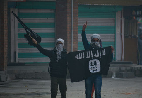 Two masked individuals with a weapon and ISIS flag.