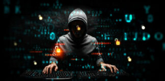 Hooded hacker using two keyboards surrounded by code.