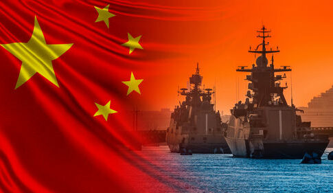 Chinese flag overlaying naval ships at sunset.