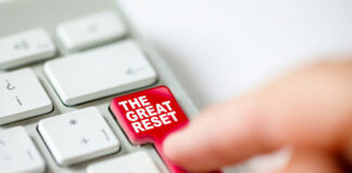 Finger pressing The Great Reset key on keyboard.