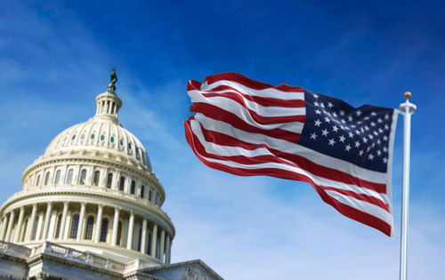 U.S. Capitol building with American flag waving in foreground.