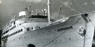 A large ship named Ukraine docked at a pier.