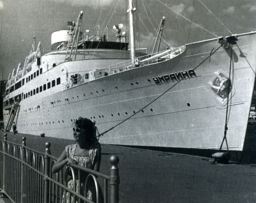 A large ship named Ukraine docked at a pier.