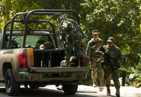 Soldiers loading equipment into a military vehicle in forest.