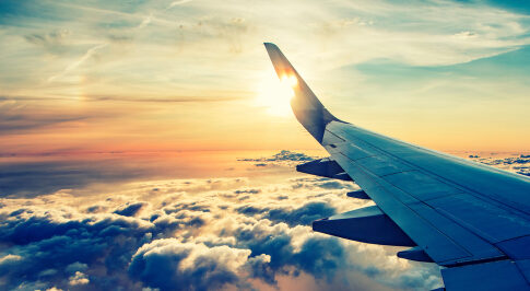 Airplane wing over cloudy sunset sky.