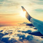 Airplane wing over cloudy sunset sky.