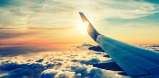 Airplane wing over cloudy sunset sky.