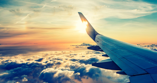 Airplane wing over cloudy sunset sky.