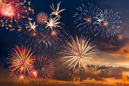 Colorful fireworks display against a darkening evening sky.
