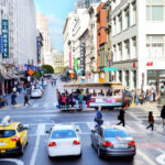 Busy San Francisco street with cable car and pedestrians.