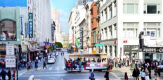 Busy San Francisco street with cable car and pedestrians.