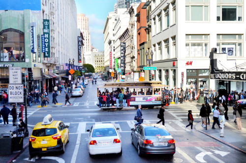 Busy San Francisco street with cable car and pedestrians.