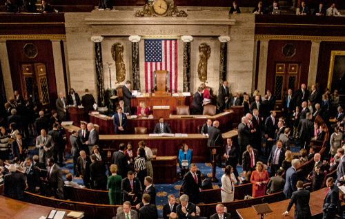 shutterstock_1186368265.jpg featured image Large group in U.S. Congress chamber, American flag displayed.