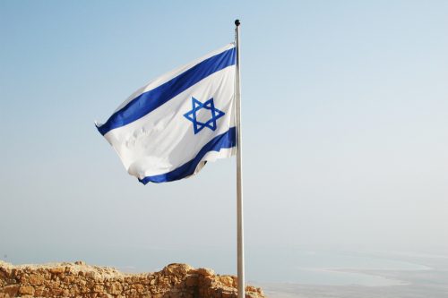 shutterstock_1219765513.jpg featured image Israeli flag waving against clear sky background.