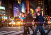 A family crossing a busy street at night.