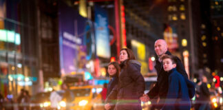 A family crossing a busy street at night.