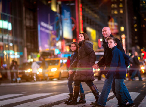A family crossing a busy street at night.
