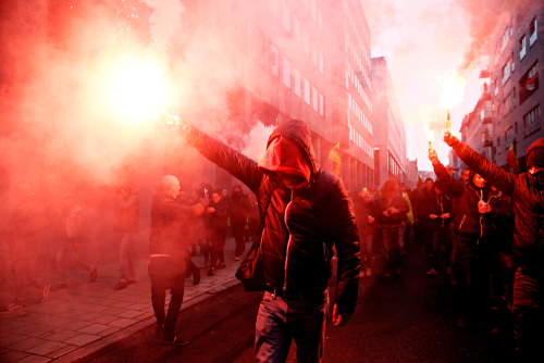 shutterstock_1288063057.jpg featured image Protesters with flares walk through smoky urban street.
