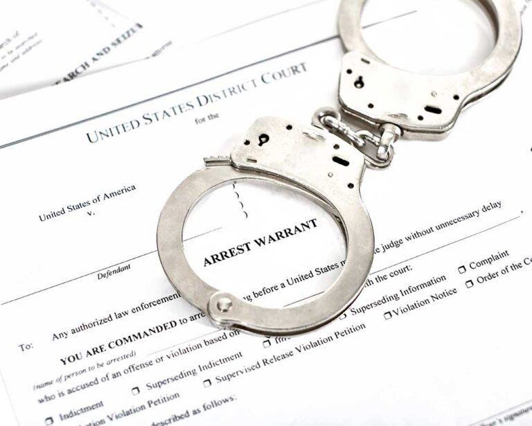 Handcuffs on an arrest warrant document