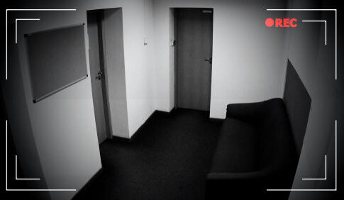 CCTV footage of an empty hallway with doors and sofa.