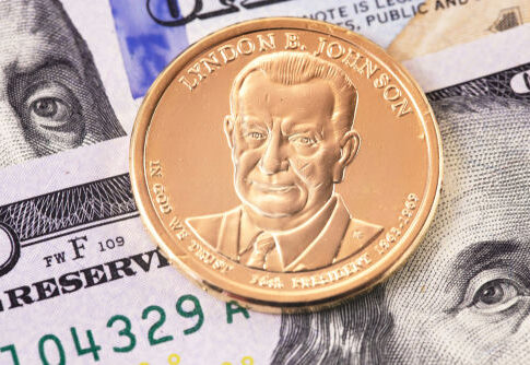 Lyndon B. Johnson coin on top of dollar bills.