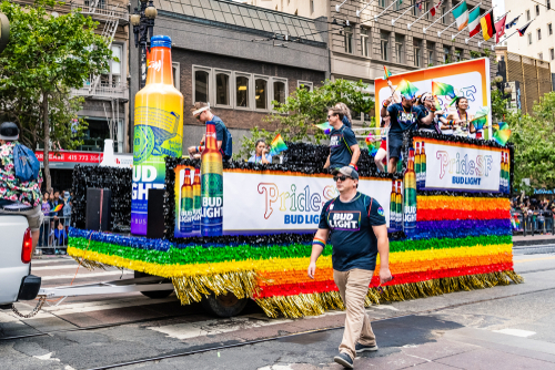 Pride parade float with rainbow colors and Bud Light logos.