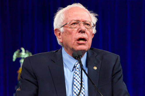 shutterstock_1486814015.jpg featured image Bernie Sanders speaking at an event, wearing a suit.