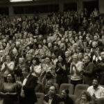 Audience giving a standing ovation in theater.