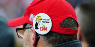 Person wearing a pin with Donald Trump and CNN logo.