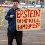 Man holding "Epstein didn't kill himself 2020" sign.