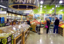 People shopping in a grocery store produce section.