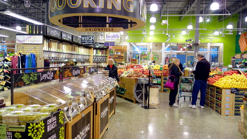 People shopping in a grocery store produce section.