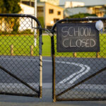 School closed sign on a gated fence.